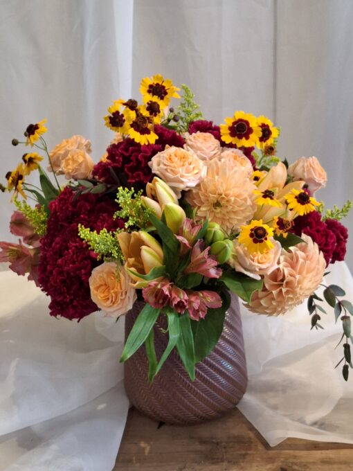 This Autumn mix combines peach dahlias, red cockscom, orange Peruvian lily, roses and fall color fillers.