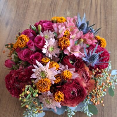This stunning fall arrangement is filled with ranunculus, thistle, spray roses, mini marigolds, alstromeria, celosia, seeded eucalyptus in a 8.5" square wooden box.