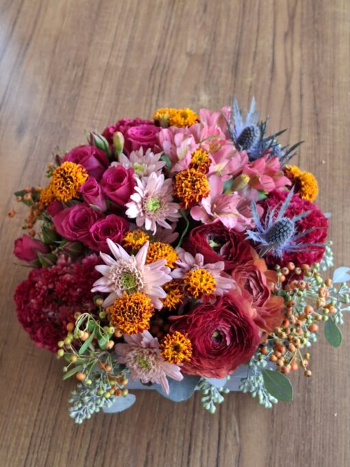 This stunning fall arrangement is filled with ranunculus, thistle, spray roses, mini marigolds, alstromeria, celosia, seeded eucalyptus in a 8.5" square wooden box.
