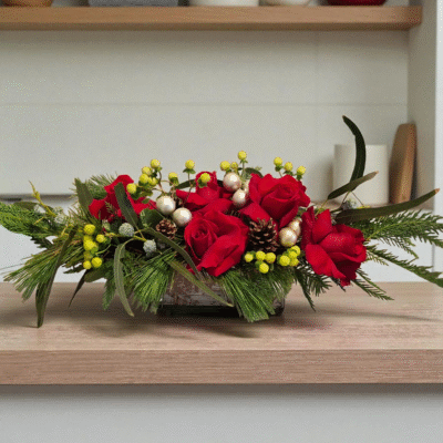 A Stunning Christmas centerpiece with red roses, green coffee beans, stem balls, Christmas greens in a rectangular glass vase would look incredible on any holiday table.