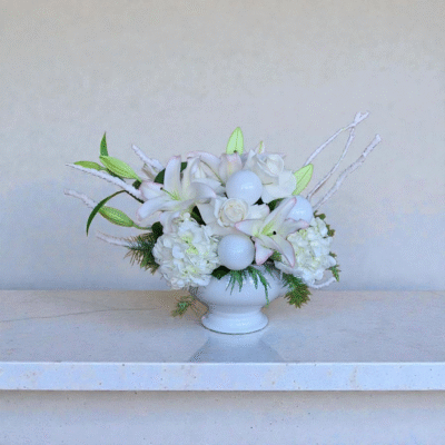 White Christmas lilies with roses, hydrangeas, white Christmas balls, snowy branches and Christmas greens.
