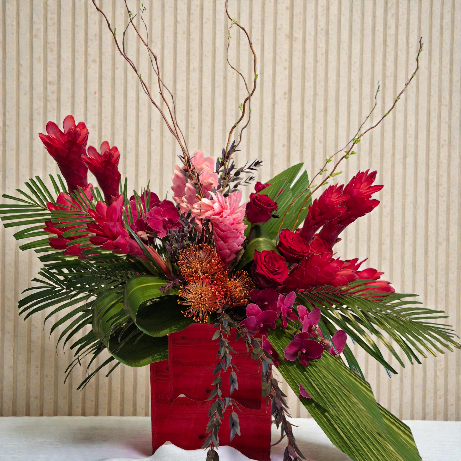 This stunning arrangement is filled with green and red luxury, with ginger, pin cusion Proteas, Roses, Orchids and tropical foliage you're sure to get an incredible reaction from this paradise of love.